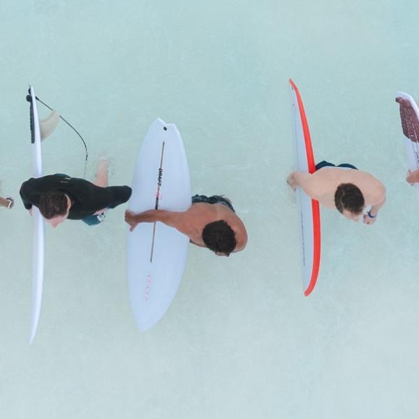 aerial shot of three men with surfboards knee deep in water