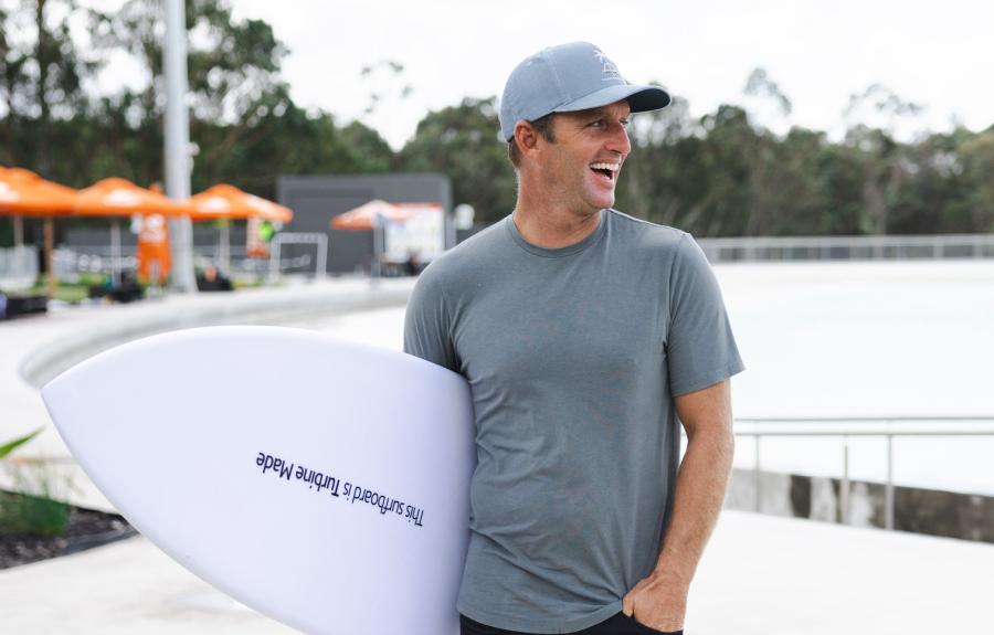 Pro surfer Josh Kerr with board made from re-purposed wind turbine under his arm