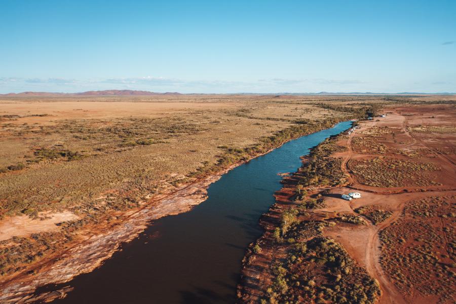 Panoramic shot of inland Balla Balla River in the Pilbara with banks either side and a small caravan at a campsite