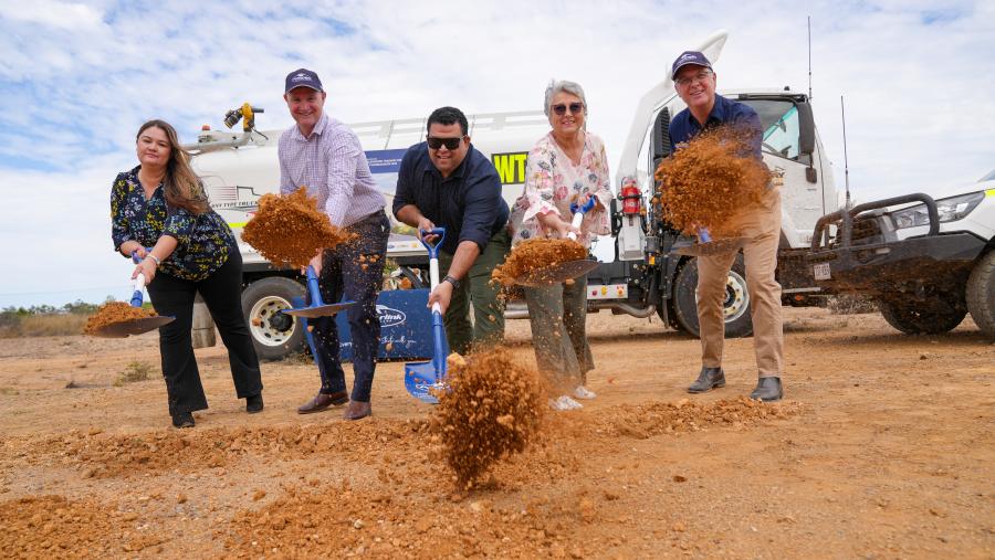 Five people turning the sod in front of the truck