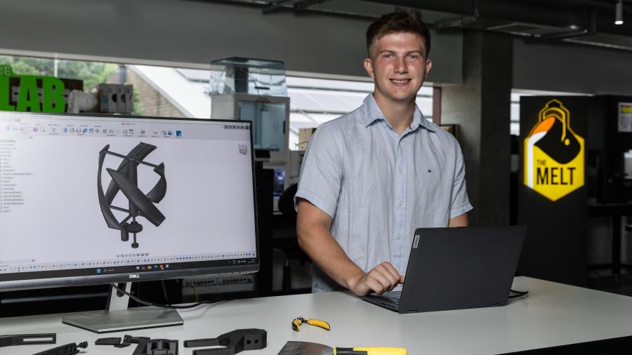 Young mans standing at science bench with laptop and prototype of wind turbine