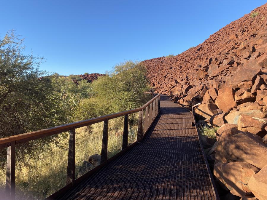 A walkway between bushlands and rocks