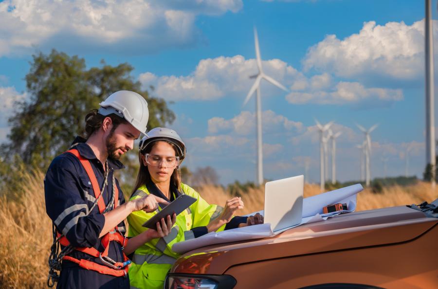 Two professional maintenance engineers in front of wind turbines