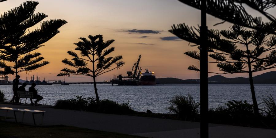 Gladstone port at sunset with silhouetted trees and a tanker