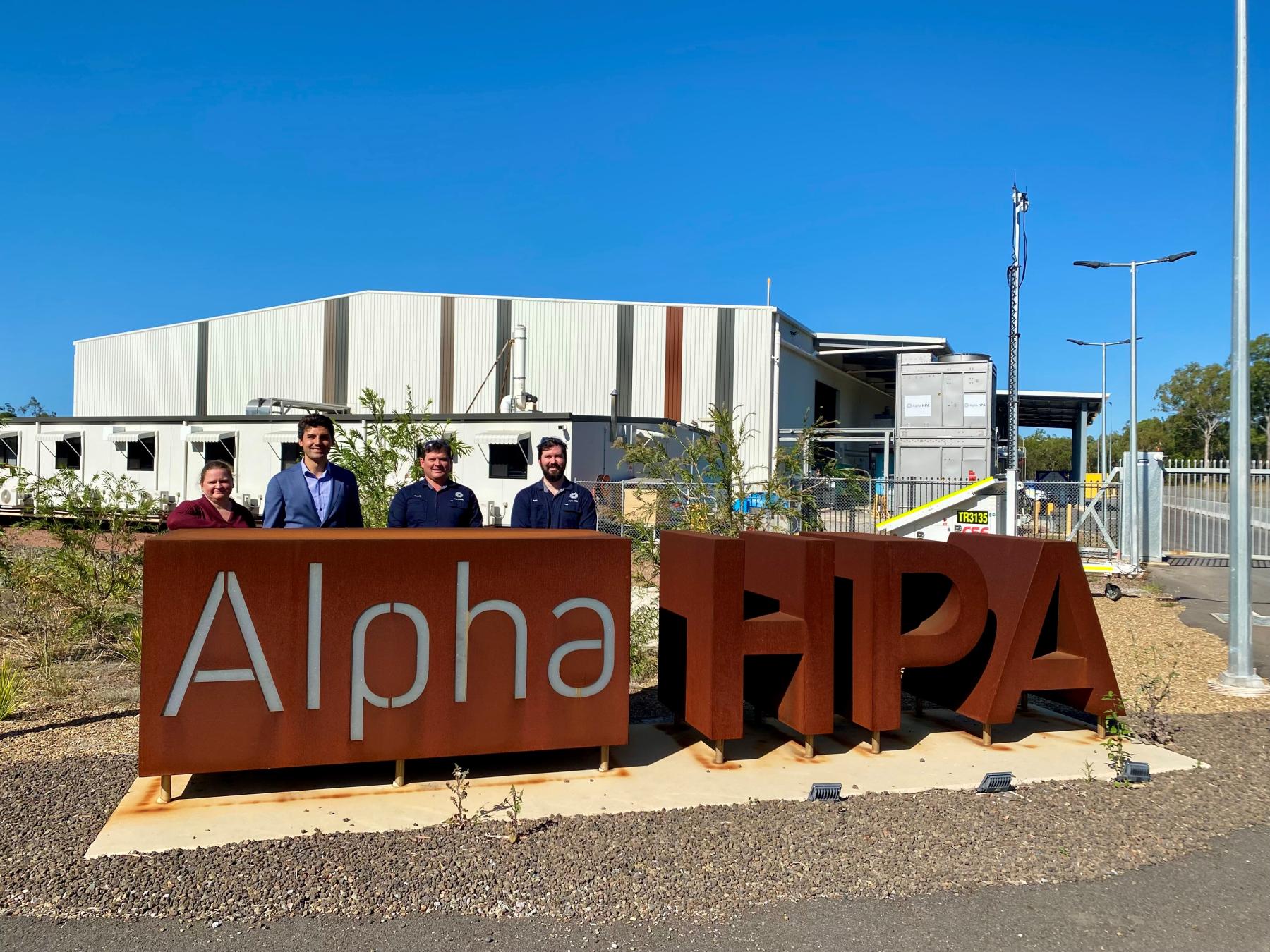 four people stand behind a large sign that says 'Alpha HPA'