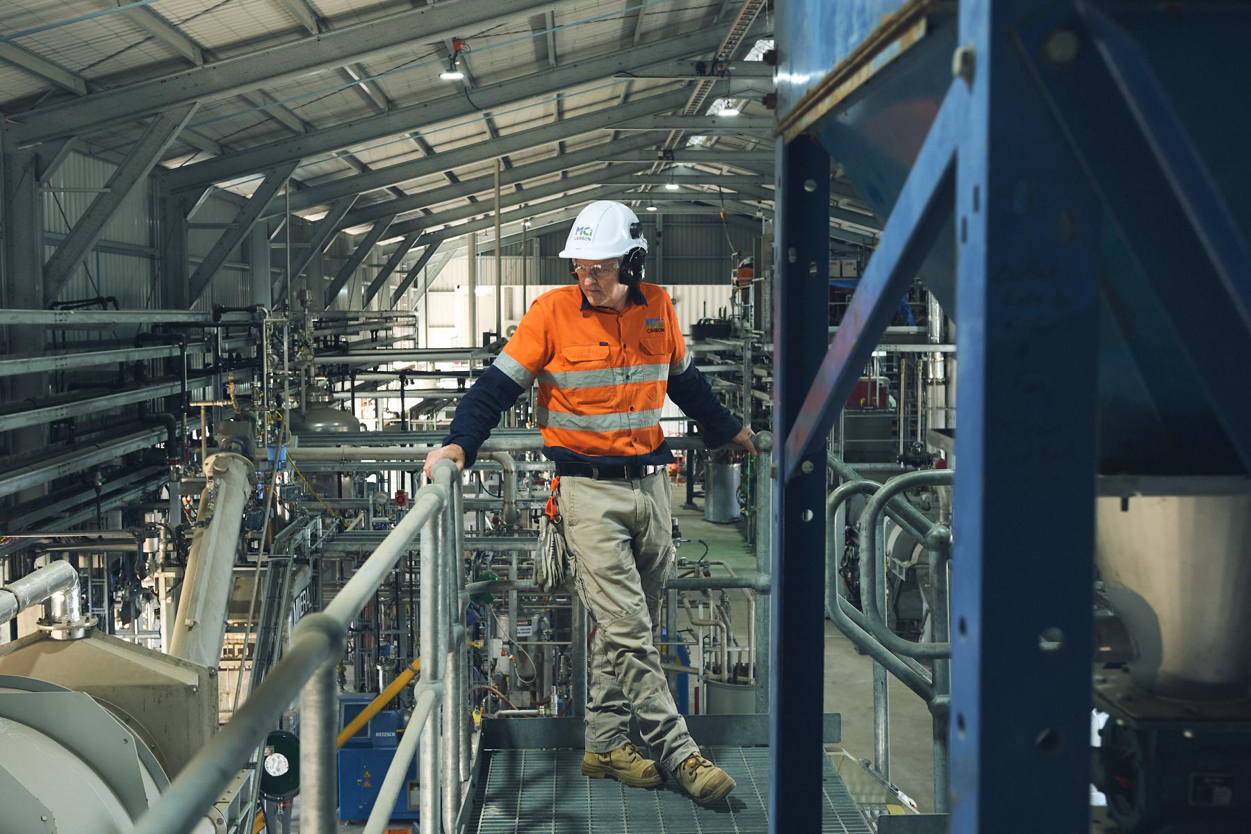 Man in high-vis safety gear looking over an industrial facility