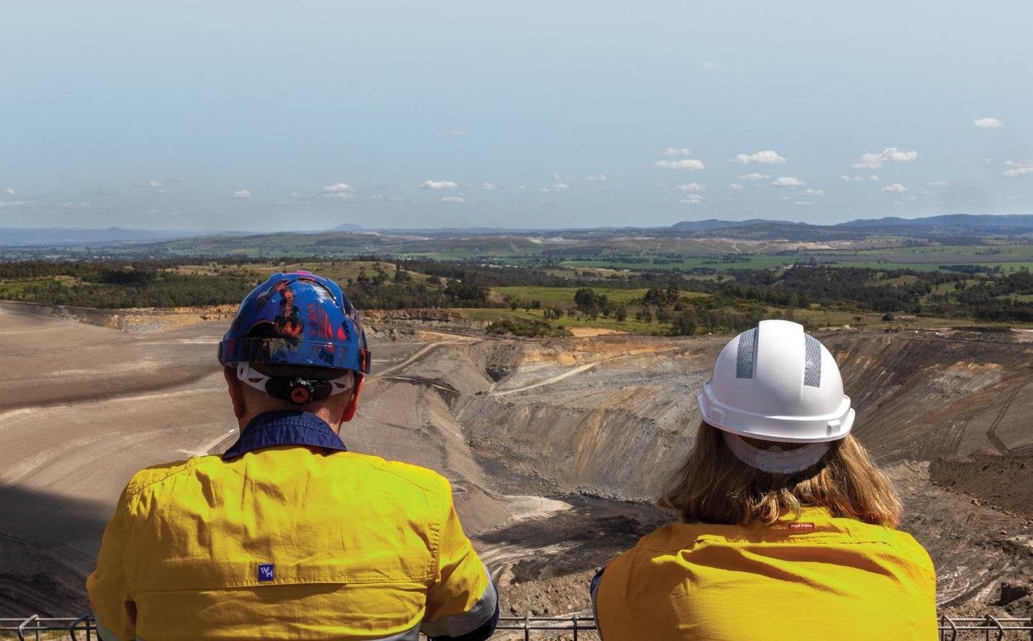 Two people in high-vis safety gear look over a mine