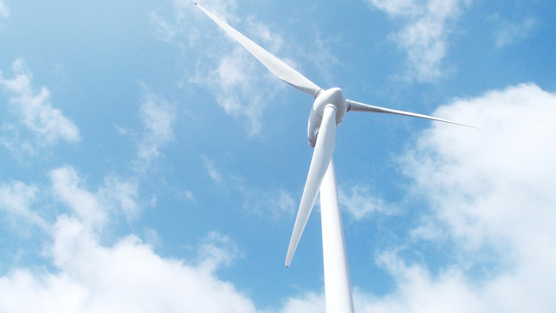 A wind turbine against a blue cloudy sky