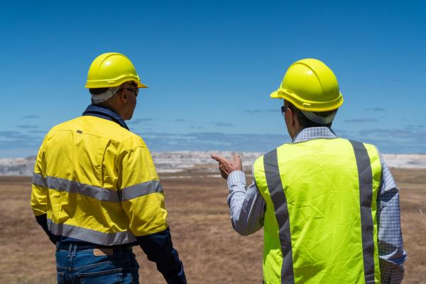 Two workers look out across a plain