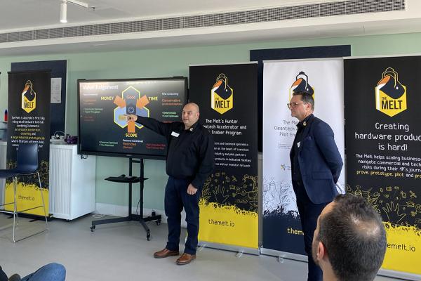 Two men presenting in front of a screen and 'The Melt' banners
