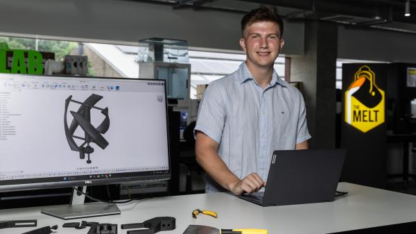 Young mans standing at science bench with laptop and prototype of wind turbine