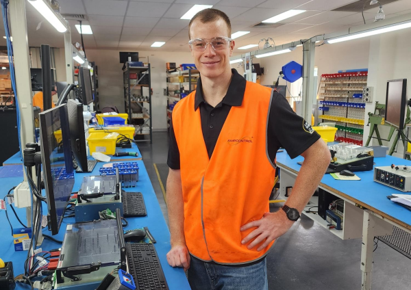 Young male engineer in high vis stands at his work bench