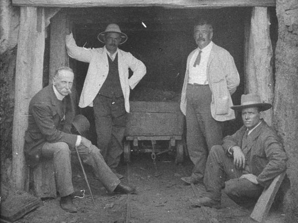 Black and white image of four men standing in front of a coal mine