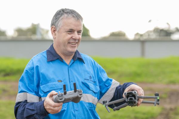 Man in blue shirt holds drone. 