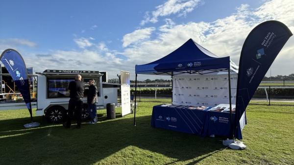 Two men at a mobile screen set up next to a NZEA branded gazebo